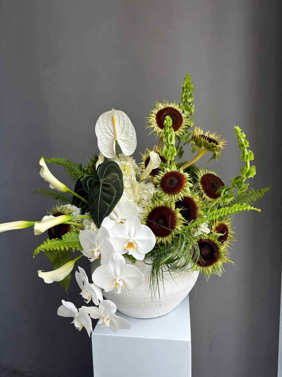 Interior Arrangement “Modern Muse” — orchid, anthurium, sunflower, calla lilies